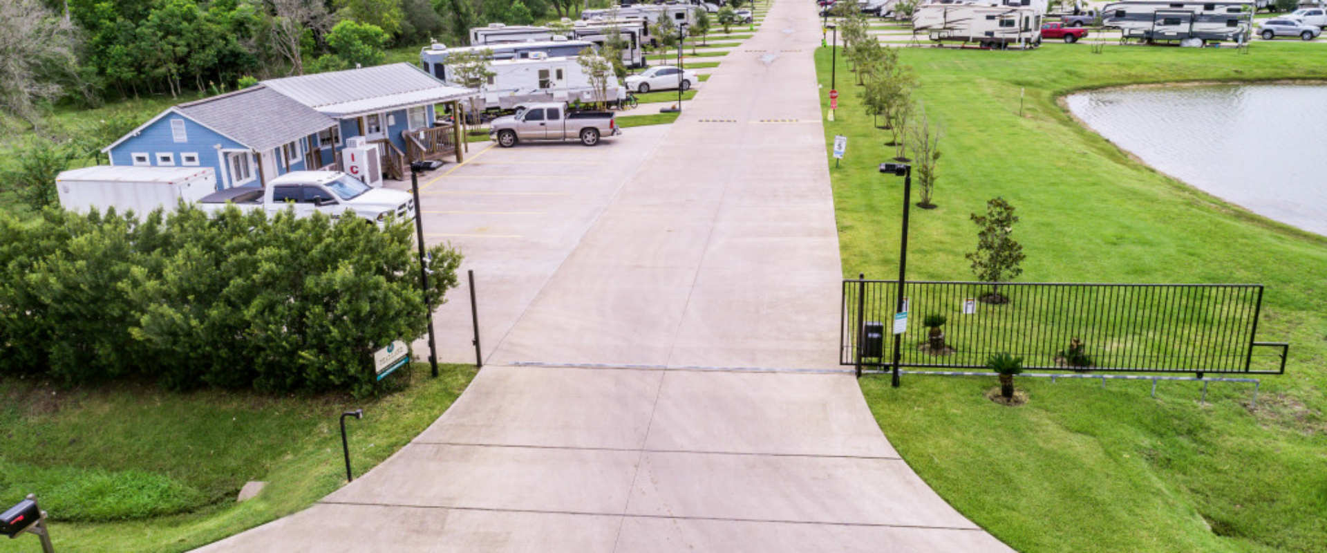 RV Park with gated entrance, lush green grass and many parking spaces.