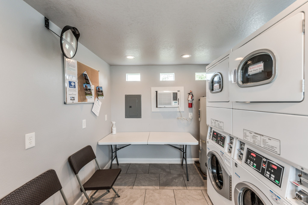 Indoor stacked washers and dryers with folding table and chairs.